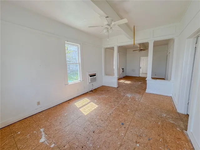 an empty room with windows and ceiling fan
