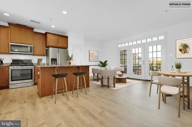 a living room with stainless steel appliances kitchen island granite countertop furniture and a wooden floor