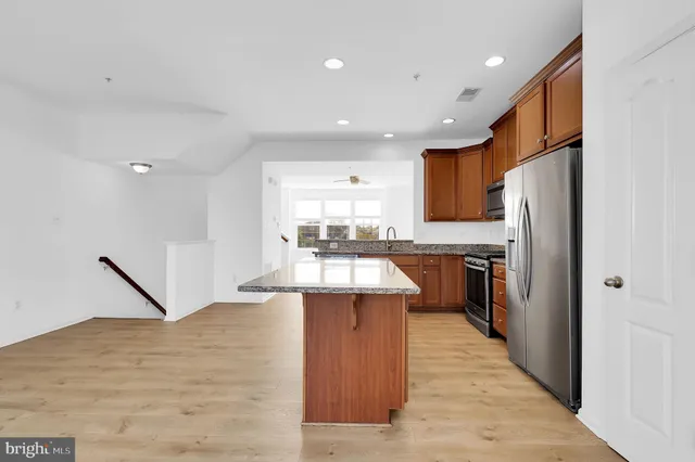 a large kitchen with stainless steel appliances kitchen island granite countertop a refrigerator and a sink