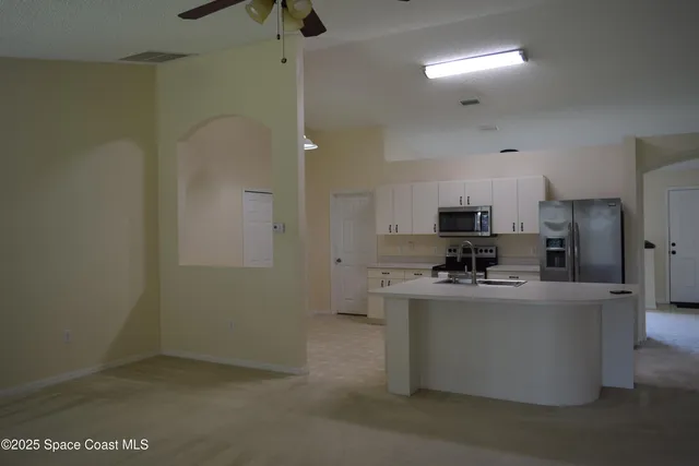 a kitchen with stainless steel appliances a refrigerator a stove a sink dishwasher a oven with white cabinets and wooden floor