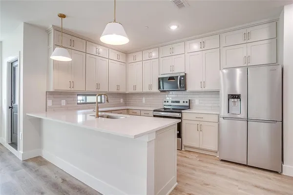 a kitchen with kitchen island white cabinets and stainless steel appliances
