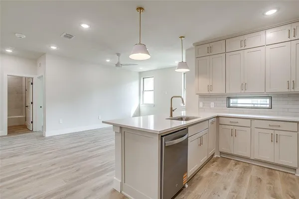 a kitchen with stainless steel appliances granite countertop a sink a stove a refrigerator and island with wooden floor