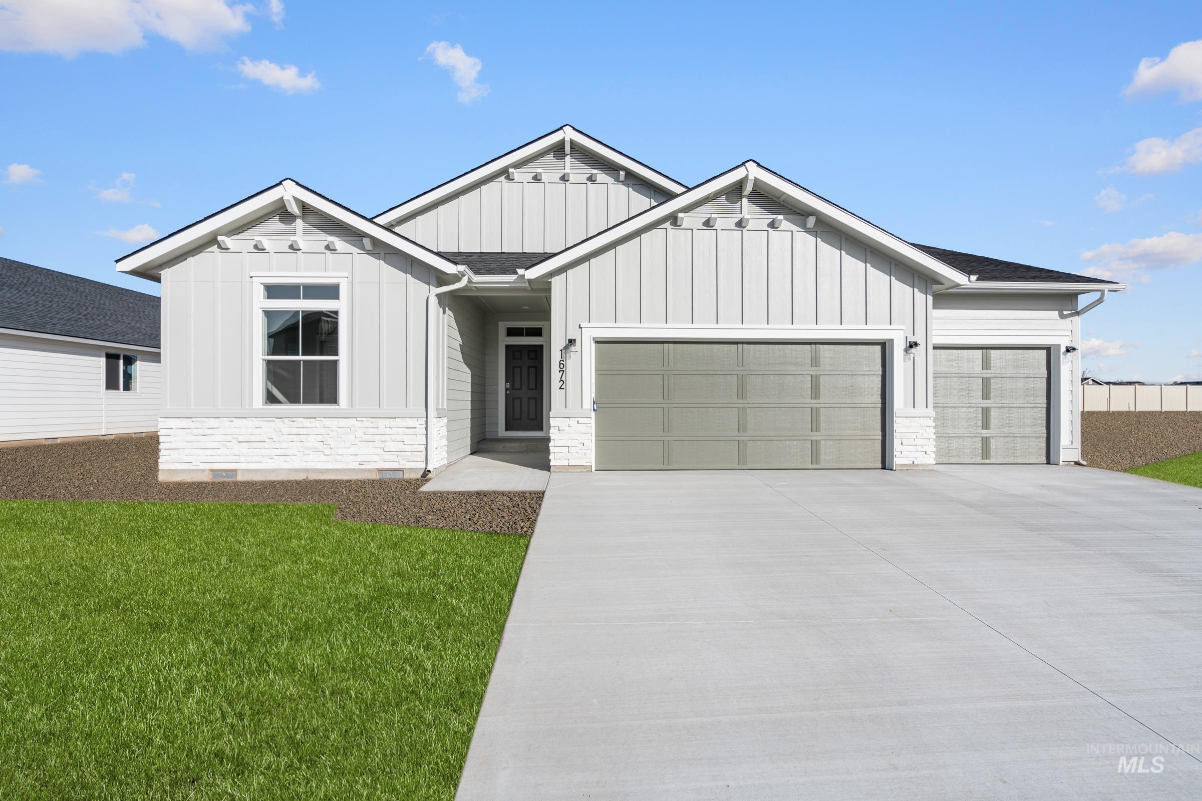 View of front of property with board and batten siding, an attached garage, stone siding, and concrete driveway