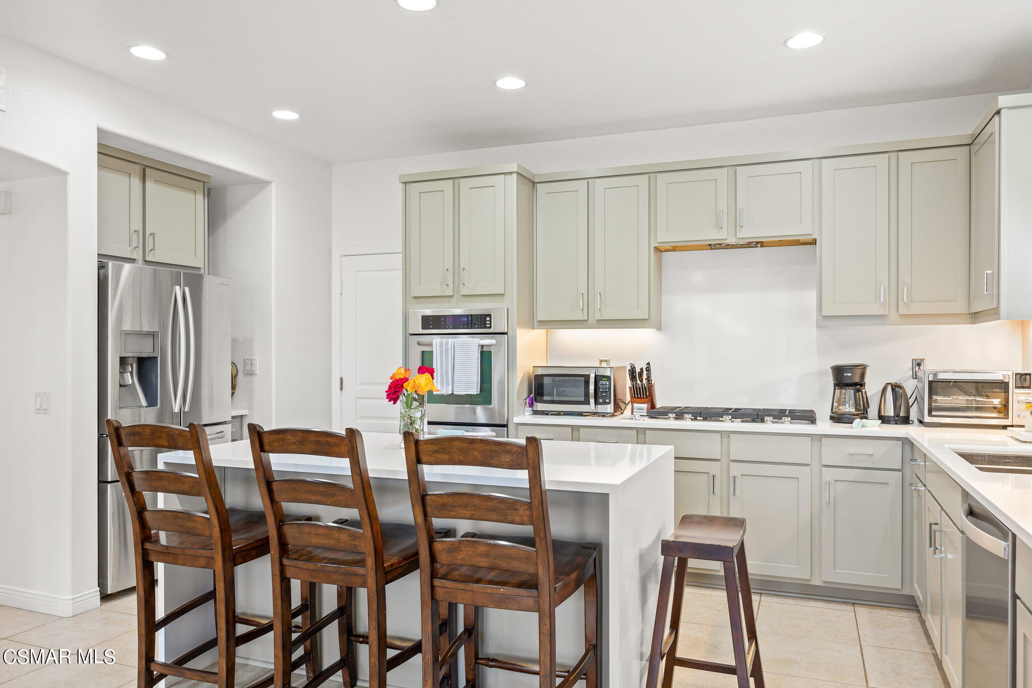 388 Woodland Road Simi Valley, CA 93065 - Photo 19 of 62 a kitchen with stainless steel appliances kitchen island granite countertop a table chairs sink and white cabinets