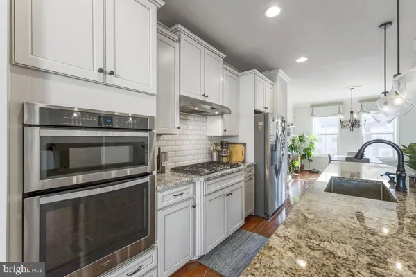 a kitchen with stainless steel appliances granite countertop a stove a sink and a microwave