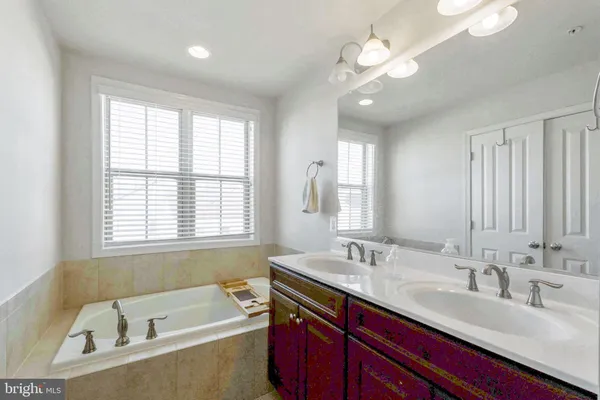 a bathroom with a tub a sink double vanity and windows