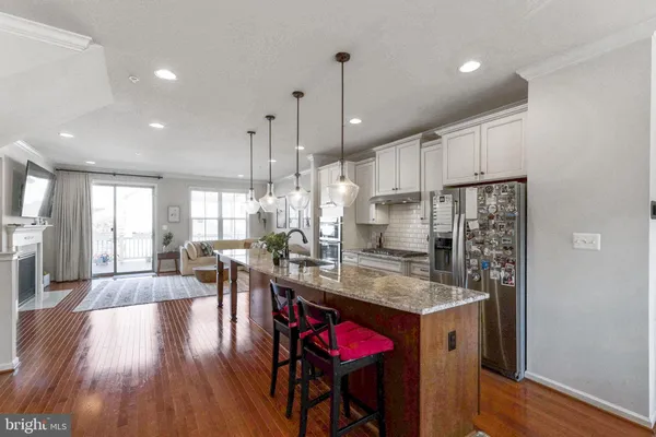 a kitchen with stainless steel appliances granite countertop wooden floors stove refrigerator and cabinets