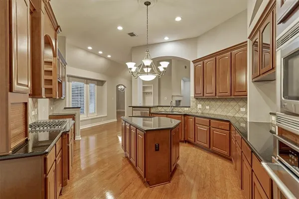 a kitchen with stainless steel appliances granite countertop a stove a sink dishwasher and a refrigerator with wooden floor