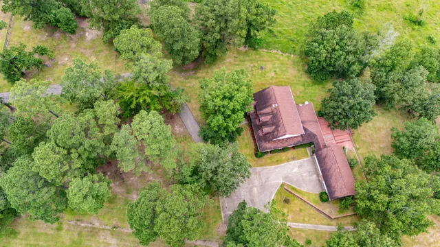 an aerial view of a house with a yard and large trees all around
