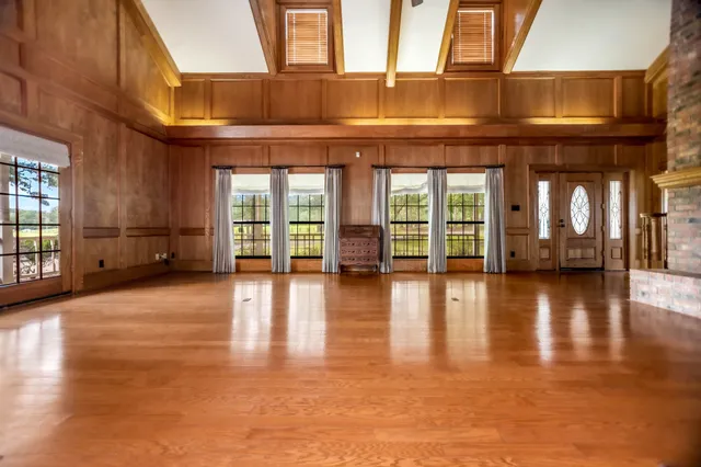 an empty room with wooden floor and a floor to ceiling window