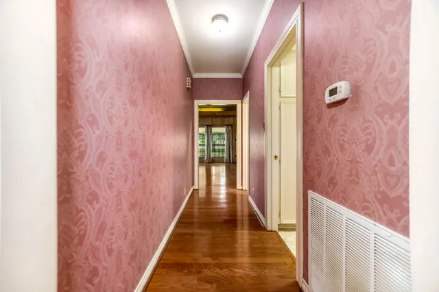 a view of a hallway with wooden floor and a bathroom