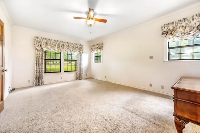 an empty room with windows and ceiling fan