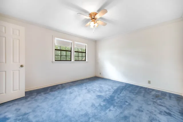 an empty room with windows and chandelier fan