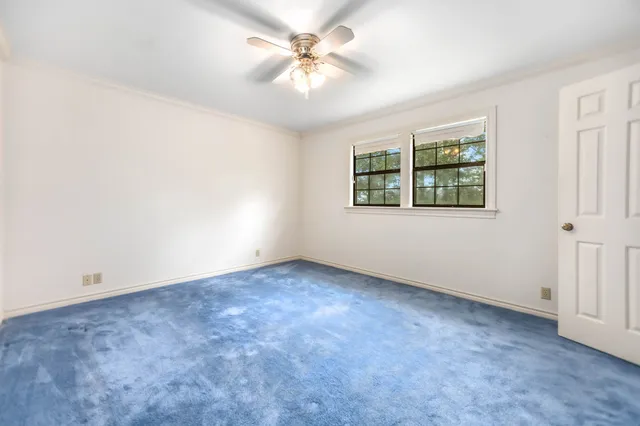 an empty room with windows and ceiling fan