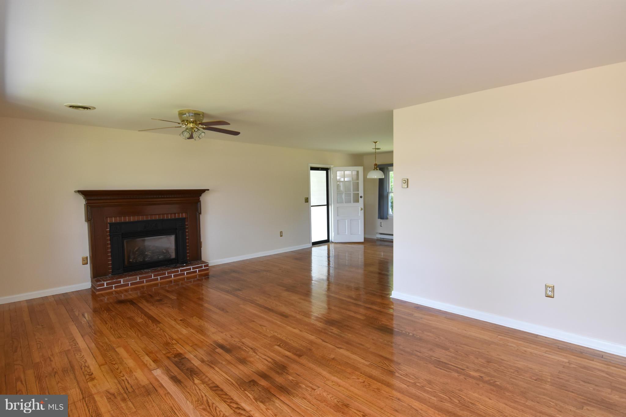48632 Wynne Road Ridge, MD 20680 - Photo 4 of 30 a view of an empty room with wooden floor and a fireplace