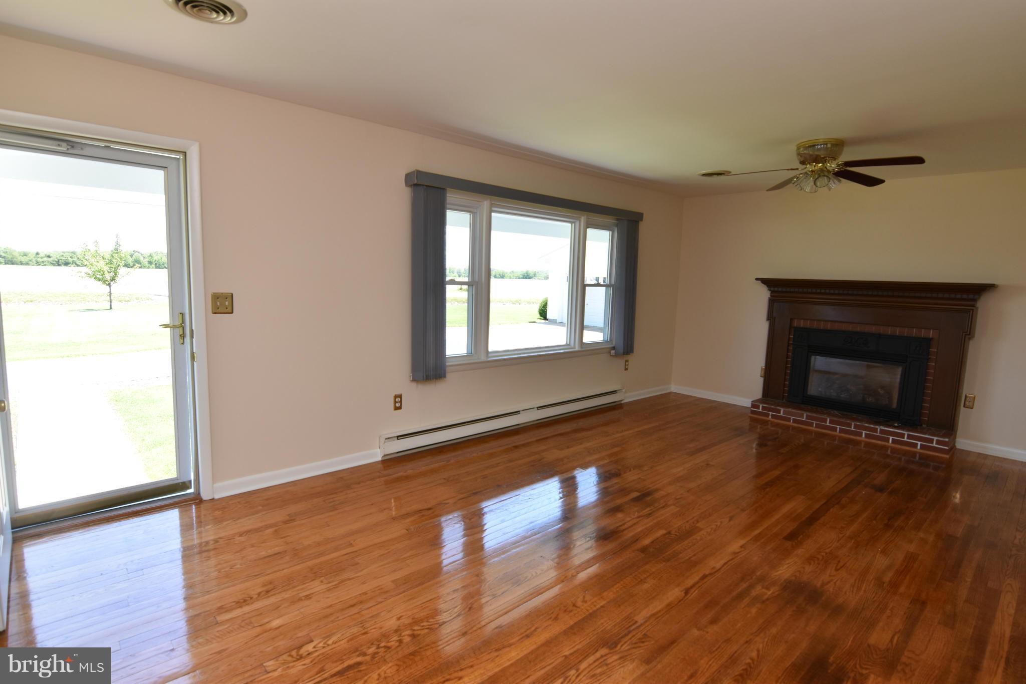 48632 Wynne Road Ridge, MD 20680 - Photo 5 of 30 a view of an empty room with wooden floor fireplace and a window