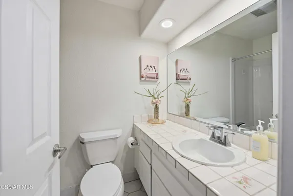 a bathroom with a granite countertop toilet sink and mirror