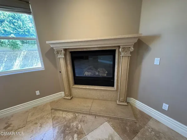 a view of an empty room with window and fireplace