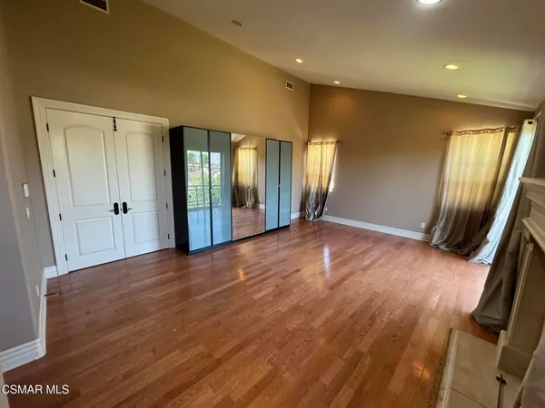 an empty room with wooden floor and mirror