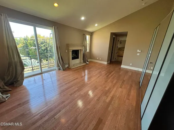 a view of empty room with wooden floor and fireplace