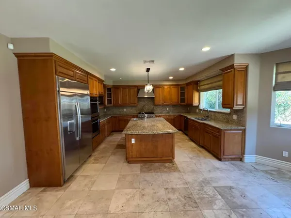 a large kitchen with stainless steel appliances kitchen island granite countertop a refrigerator and a sink
