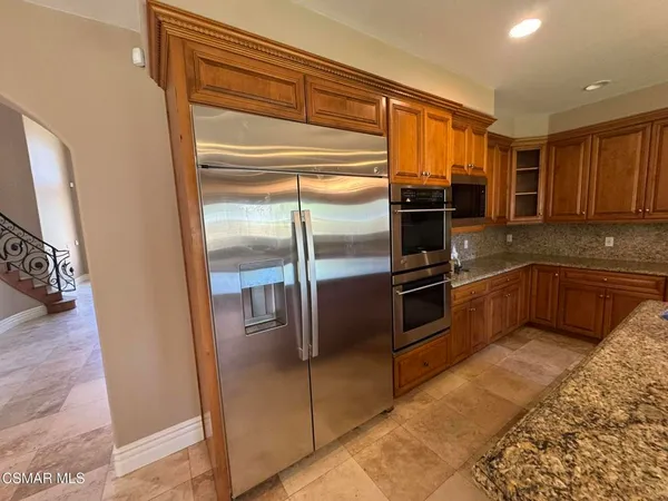 a kitchen with granite countertop a refrigerator and a stove top oven
