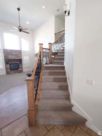 552 Sunset Crest Way Draper, UT 84020 - Photo 18 of 68 Stairs featuring ceiling fan, a stone fireplace, recessed lighting, and stone tile flooring
