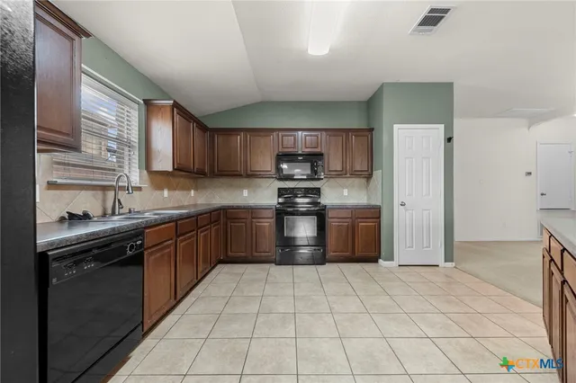 a kitchen with stainless steel appliances granite countertop a stove a sink and a refrigerator