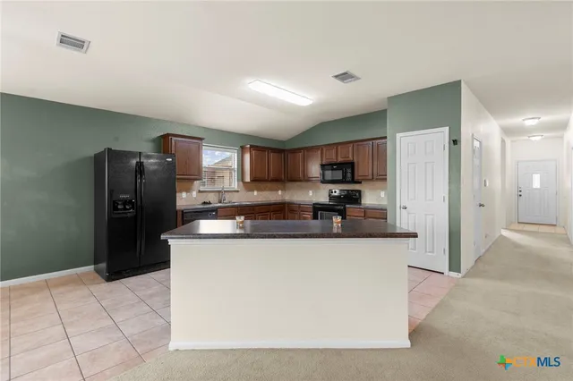 a kitchen with stainless steel appliances granite countertop a refrigerator and a stove