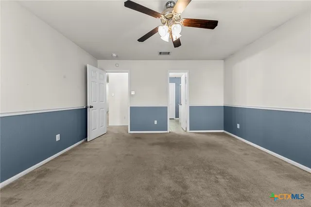 an empty room with ceiling fan and windows