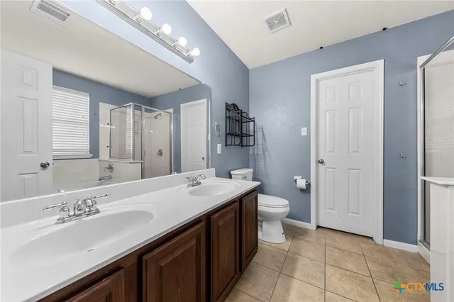 a spacious bathroom with a double vanity sink a large mirror and a shower
