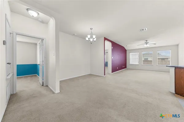 an empty room with chandelier and windows