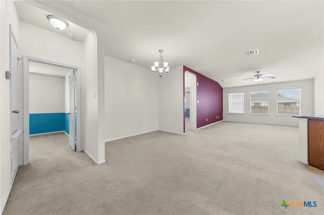 an empty room with chandelier and windows