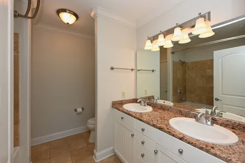 a bathroom with a granite countertop sink a toilet and a mirror