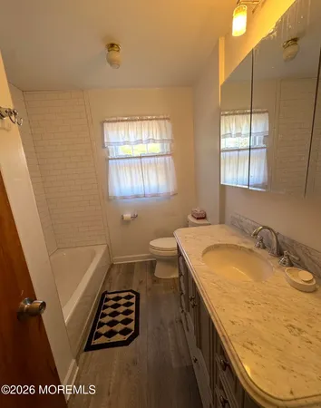 a bathroom with a granite countertop sink a toilet a window and vanity