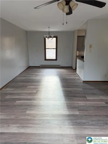 a view of an empty room with a window and wooden floor