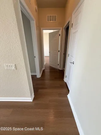 a view of a hallway with wooden floor and staircase