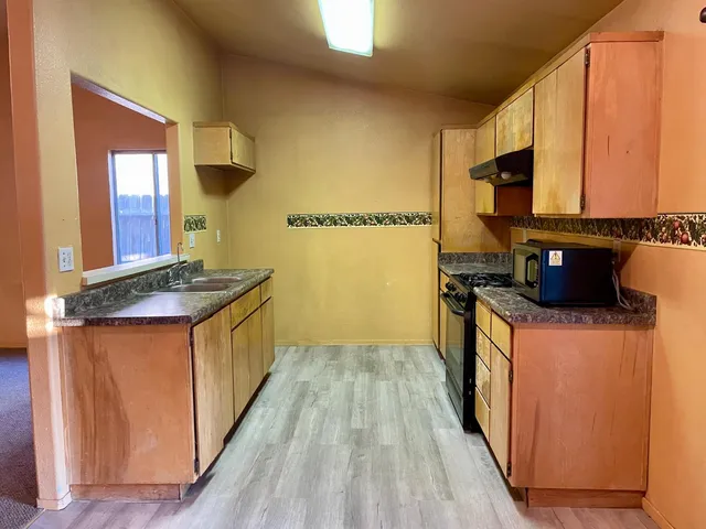 a kitchen with stainless steel appliances granite countertop a stove a sink and a microwave