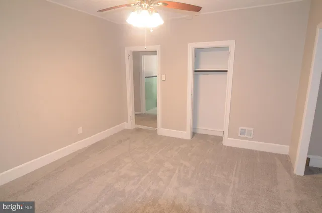 an empty room with windows and fan