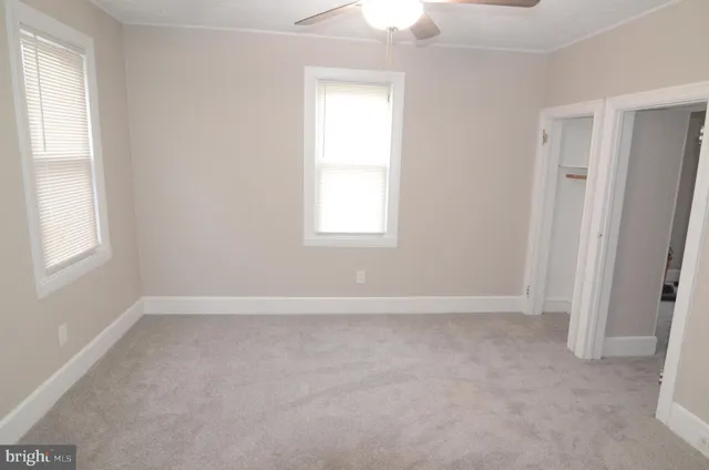 an empty room with a fan & a ceiling fan