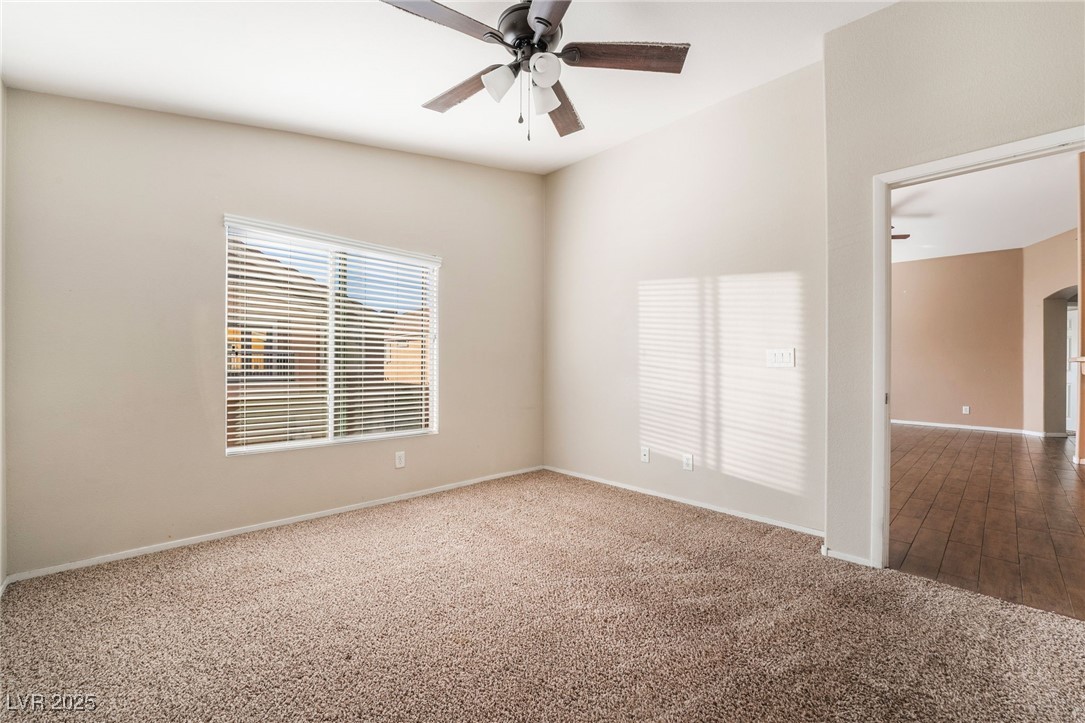 1570 Rusty Ridge Lane Henderson, NV 89002 - Photo 22 of 35 Carpeted empty room featuring arched walkways, baseboards, and ceiling fan