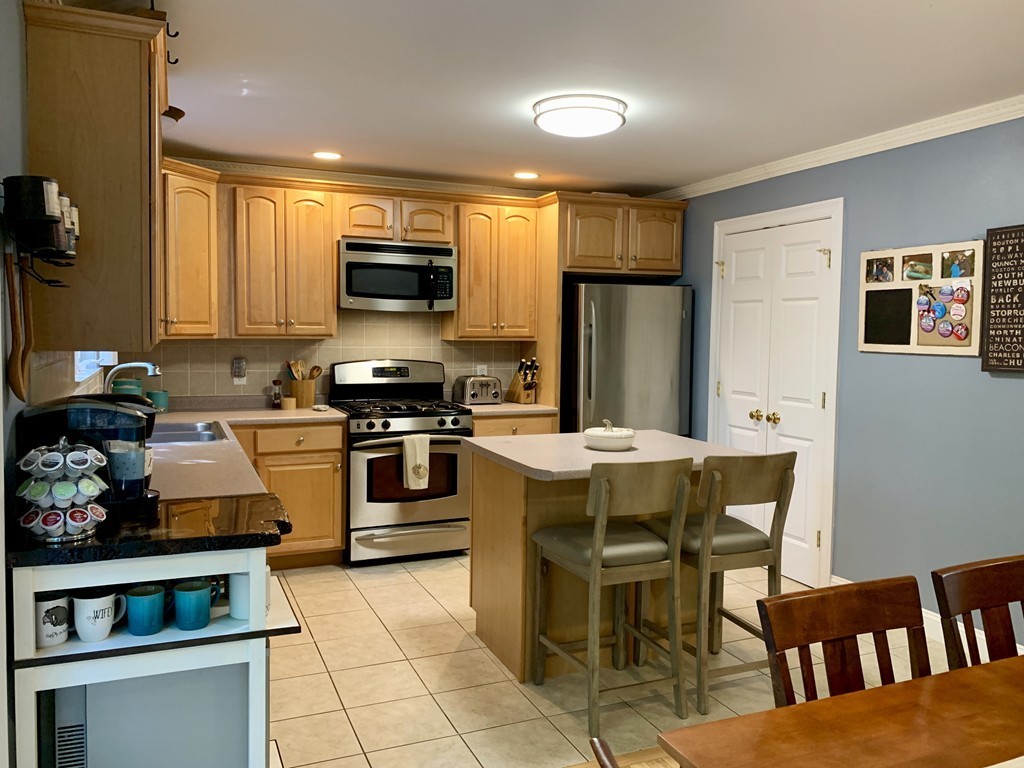 130 Turnpike Road, Unit 13 Chelmsford, MA 01824 - Photo 2 of 35 a kitchen with stainless steel appliances granite countertop a stove top oven a sink a dining table and chairs with wooden floor
