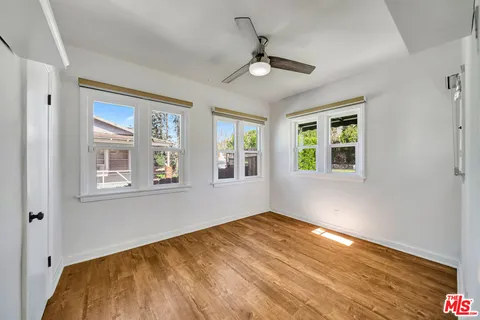 a view of empty room with wooden floor and fan