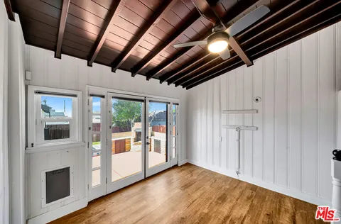 a view of an empty room with wooden floor and a kitchen