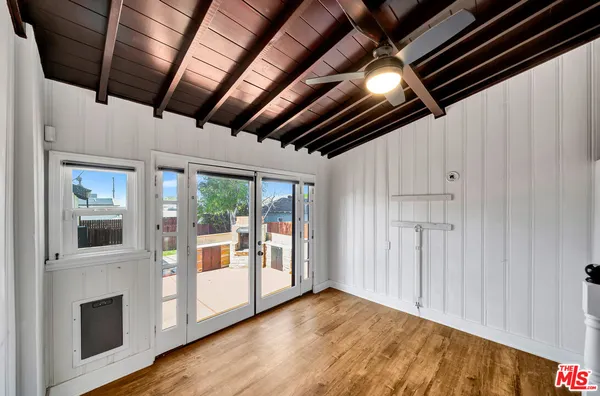 a view of an empty room with wooden floor and a kitchen
