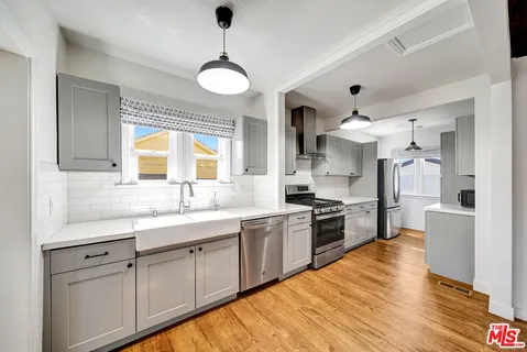 a kitchen with stainless steel appliances granite countertop a sink cabinets and wooden floor