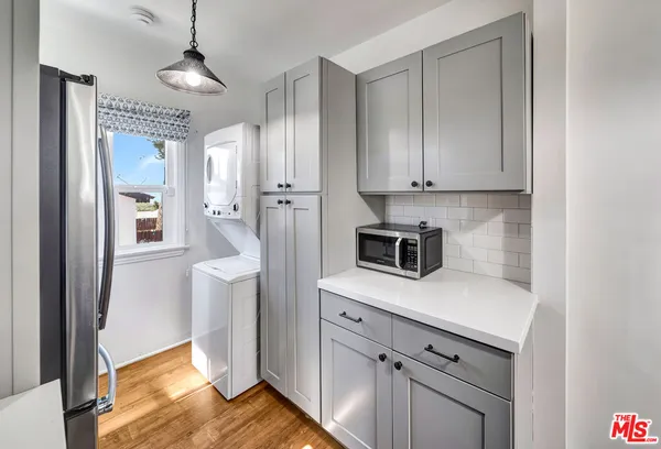 a kitchen with stainless steel appliances granite countertop a refrigerator a stove and white cabinets with wooden floor