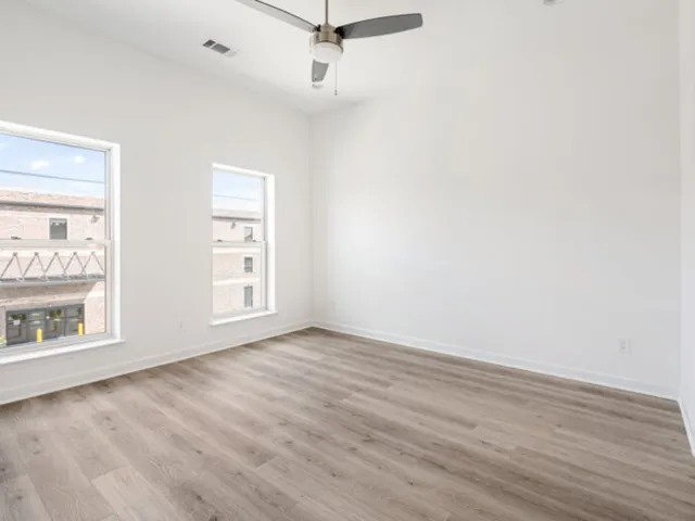 an empty room with wooden floor cabinet and windows