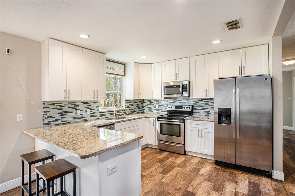 909 Silver Ridge Way Valrico, FL 33594 - Photo 5 of 15 a kitchen with kitchen island granite countertop a stove cabinets and refrigerator