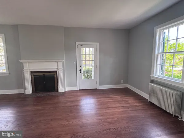 an empty room with wooden floor fireplace and windows